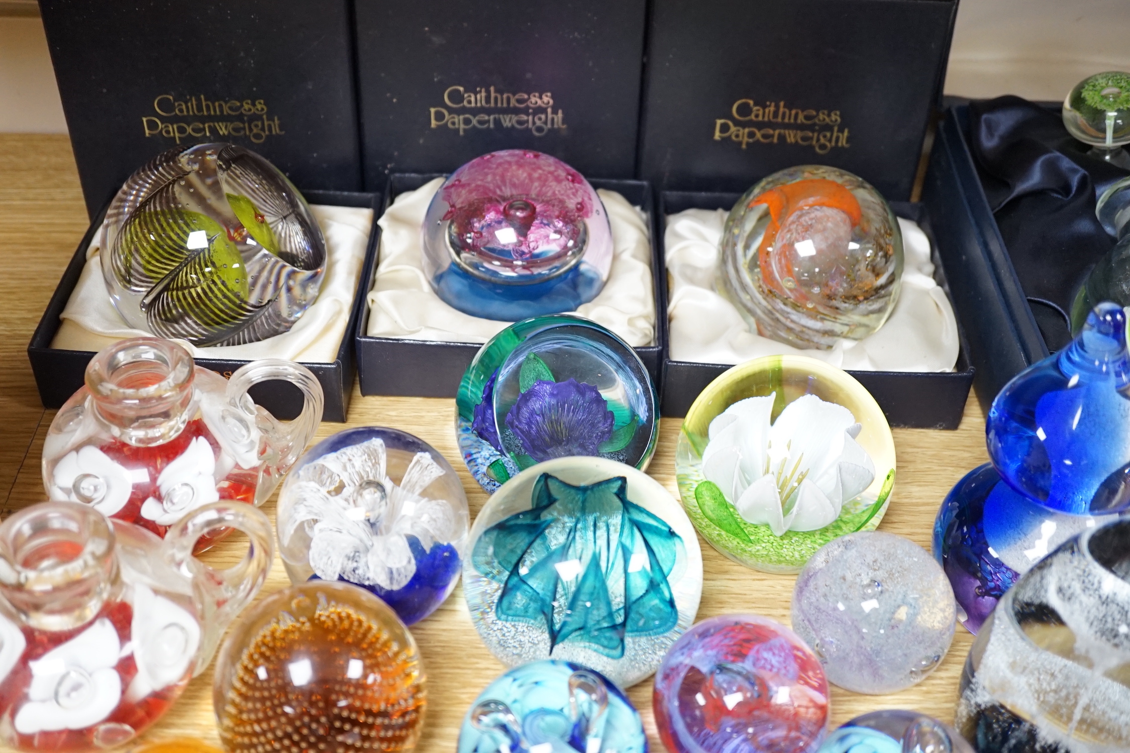 A collection of mostly Caithness glass paperweights, 1980s-2000s, with various boxes